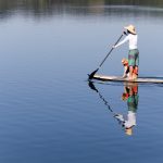 man standing on boat holding boat paddle